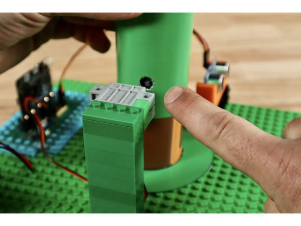 The brim of the hat does not need to be attached. The center hole is should fit around the gear rack assembly. You need only slide it down and around the gear rack before adding the tube.