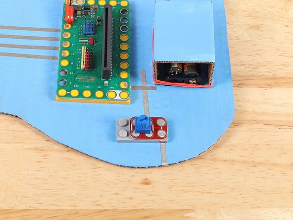Add a piece of Maker Tape under Pin 0 of the Bit Board that connects to the path from the Potentiometer. Press the Bit Board on top of the path to secure the tape in place.