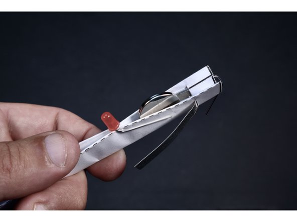 Seat the battery as shown so that the positive side is facing the only remaining unsecured Maker Tape section and the negative side is facing the only LED leg currently secured.