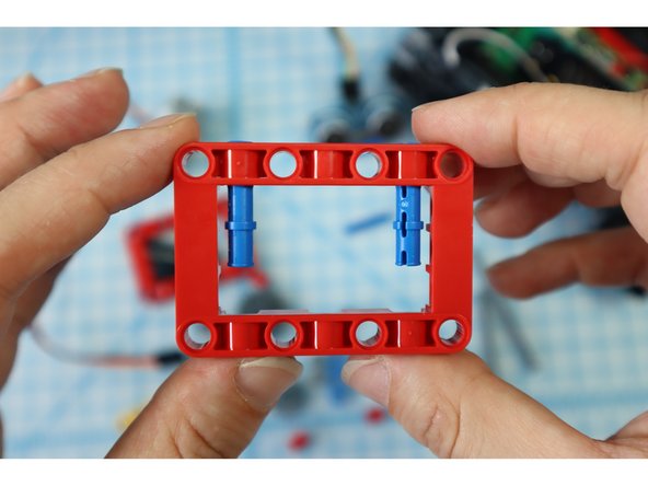 Get a red frame piece, two long pins, and the gray servo motor.