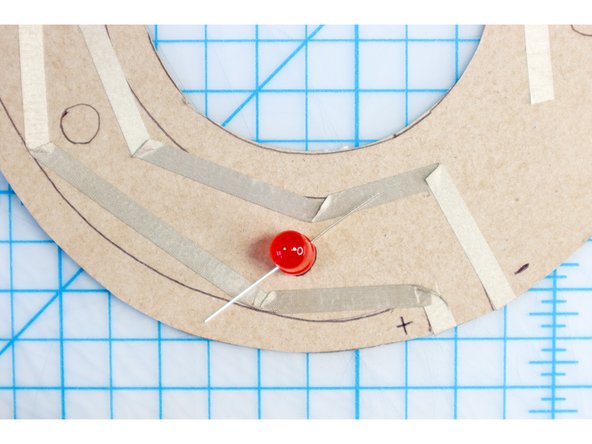 Position the LED over the circle template with the long leg touching the outer ring of  tape and the short leg touching the inner ring of tape.