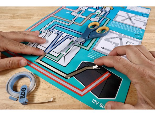Measure, cut, peel, and stick the parts of the black Maker Tape path leading into the control box on the template. Overlap each segment as you go. From here, the flow of electricity will be split into several paths to feed the three outcomes at the ROV.