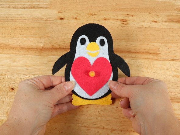 To make the Penguin look like it is holding the heart, fold the flippers inward and keep them in place with a small amount of hot glue.