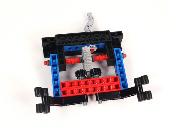 Connect the two sections by inserting the open studs on the blue bricks with holes to the bottom of the black tiles on Section 3. Check to make sure that the teeth on the black gears mesh with the large gear.