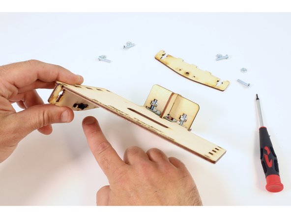 Fit the "servo horn" side brace into the lefthand slots on the side of the panel plate that is opposite the engraving so that the horn itself is oriented inward as shown in photo 2. Secure in place using two screws/nuts and your screwdriver.