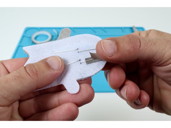 Peel and stick half of a single piece to a single LED leg as shown at left and then fold it back onto itself. This will result in the LED leg being sandwiched between the two layers.