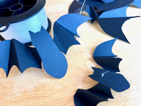 Thread about 2 feet of fishing line through the hole on each bat and tie a knot to keep it in place.