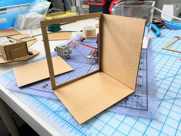 We cut out a frame of cardboard for the front of the body box, then created the side walls.