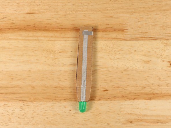 The strip of tape should NOT touch the path of Maker Tape on the back of the handle, but it SHOULD overlap with the piece of Maker Tape on the front side of the handle.