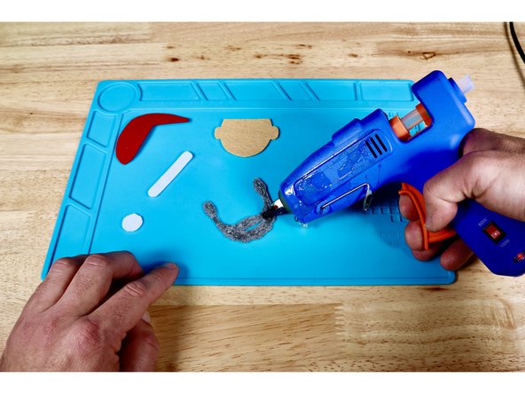 Using a hot glue gun and photo one for reference, squeeze a bead of hot glue onto the beard.