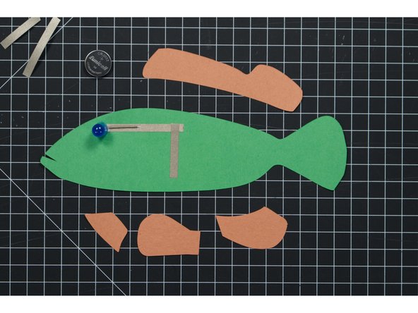 Tape down the negative LED leg (which is on the front side of the fish) using Maker Tape.