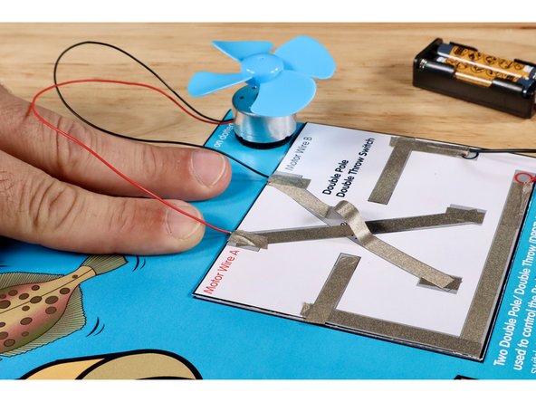 Connect the black motor wire to the end of the upper part of the criss-cross nearest to the &quot;Motor Wire B&quot; label. Use a small piece of Maker Tape that you measure, cut, peel, and stick as shown.