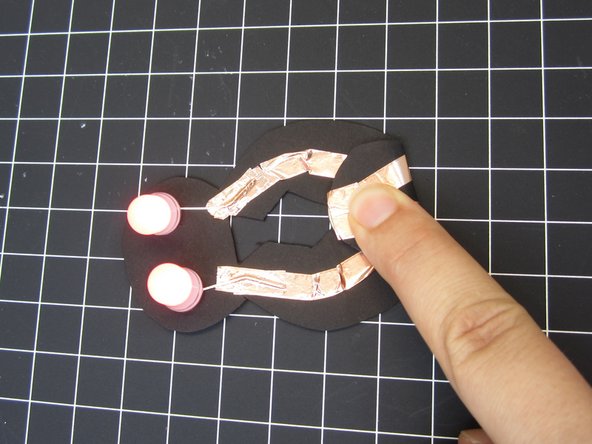Fold down the bulb on the back so that the two Positive lines of tape make contact with the top of the battery.