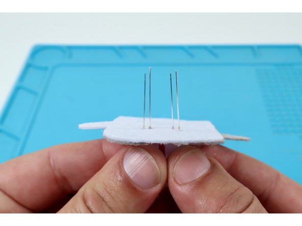 Thread the two legs of the remaining LED through the remaining pairs of holes using the same orientation of short and long legs you chose for the first one.