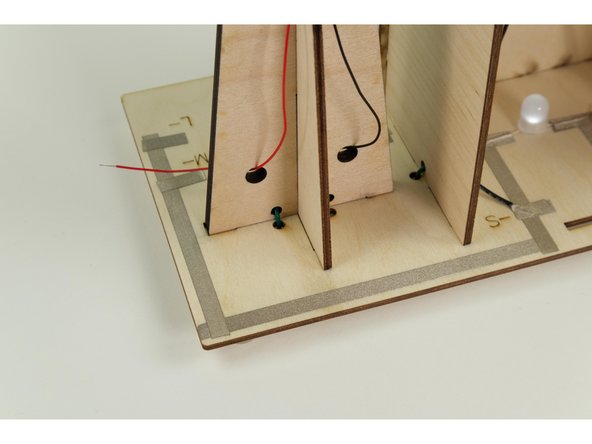 The wires attached to the motor will get connected in front of the windmill, so we'll thread the wires through the holes as shown.