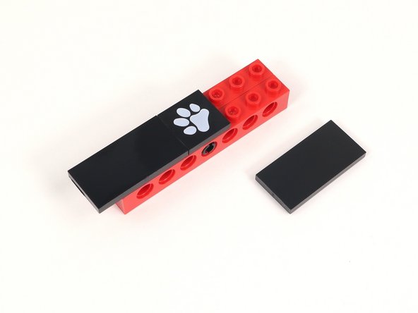 Add a 2x4 tile on either side of the paw print tile. Each of those tiles should hang off the build by one column of studs.