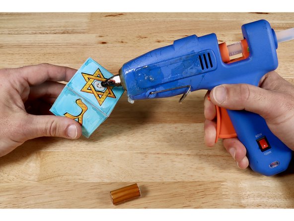 Use a hot glue gun to put a dot of hot glue in the circle at the center of the Star of David.