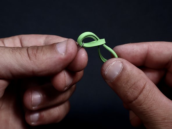 Grab one end of the rubber band and, bringing it OVER the paperclip bend, thread it through the remaining loop.