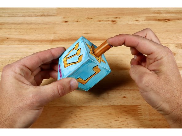 Press the finished dreidel handle onto the dot of hot glue and allow to cool before letting go.