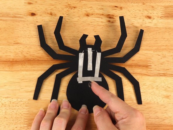 Make a loop of tape (sticky side out) using a short piece of Maker Tape, and stick it atop the middle of the tape pathway connecting the two longer (Negative) pathways.