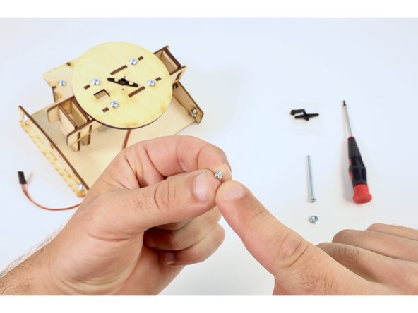 Locate one of the remaining small screws from the servo bags and thread it through the hole on the left solar panel side brace.