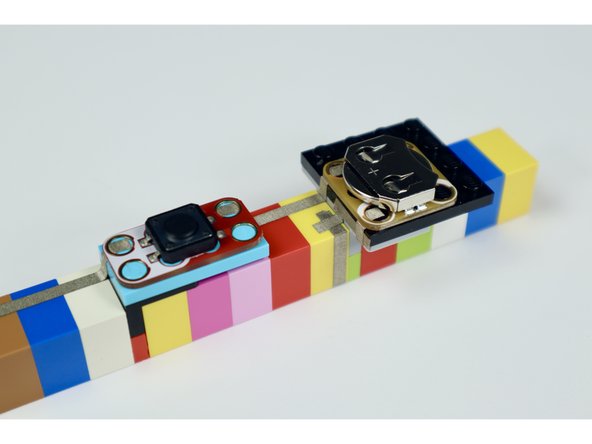 Taking care to orient each component as shown in the photos at left and press the battery holder, pushbutton and LED into place. 