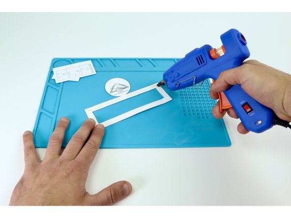 Use a hot glue gun to place hot glue on the inside of a frame while pressing the colored rectangle into place on top. Be sure to be accurate with your placement as each edge will eventually need to be fastened to the next. Overhang can make this tricky.