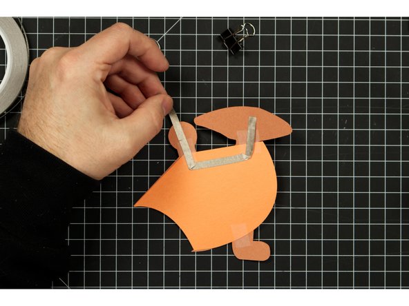 The tape should wrap around the round part to the front side of the Triceratops.