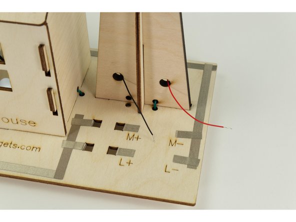 The wires attached to the motor will get connected in front of the windmill, so we'll thread the wires through the holes as shown.