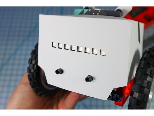 Place the paper body over the bot (hint: Move the arms to the up position, and angle it from the back to get the hole around the electronics,.)