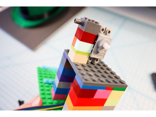 On top of the distance sensor, add another layer of LEGO to mount the servo motor. Use the LEGO Brick 2 x 2 with Pins and Axlehole (30000 / 65514)  to mount the motor on its side, as shown.