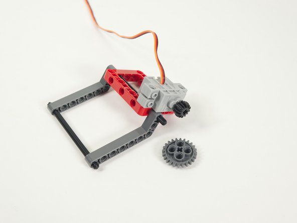 Add the large gray gear to the portion of the axle that is sticking out.