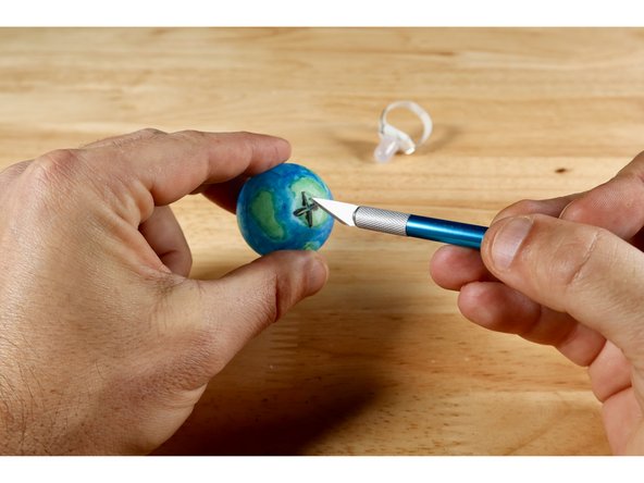After you've colored your design (all over designs are best), use an Xacto knife to carefully (your parent may like to help you here) cut two 1/4" slits that cross one another at the bottom of your ball.
