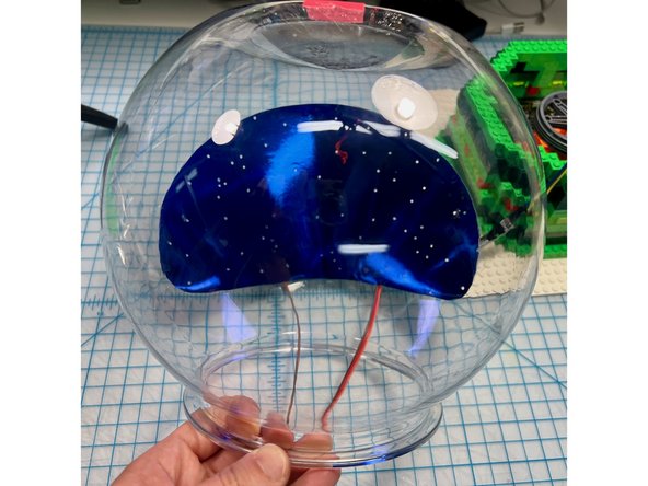 I taped NeoPixel sticks to the back and covered them with a layer of shiny blue cardstock that I punched holes out of to give the appearance of many light-up stars.