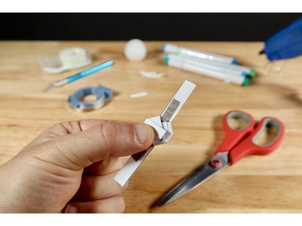 To electrically separate the LED from the rest of everything below you should fold each of the six tabs over the battery one at a time and pinch them in place with one hand.