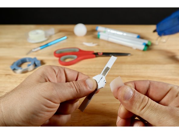 Use a small piece of clear tape to secure those tabs. Use a scissors to trim the excess afterward. Now anything conductive that we place on top will not contact anything below unless we want it to.