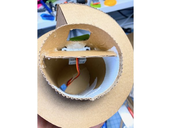 We added a piece of cardboard at an angle to rebound the gumball toward the person's hand.