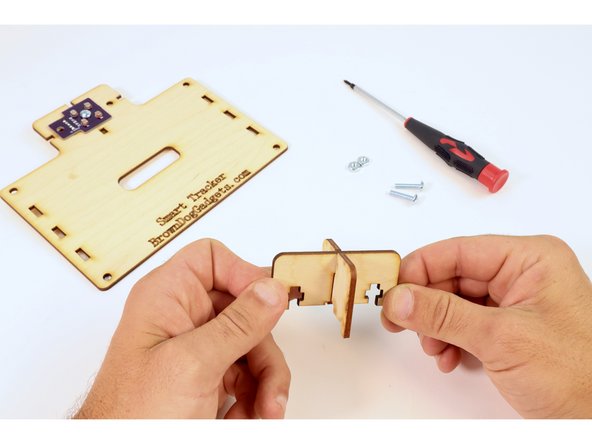 Fit the two small wood pieces together as shown by sliding the larger of the two pieces atop the smaller via slots.
