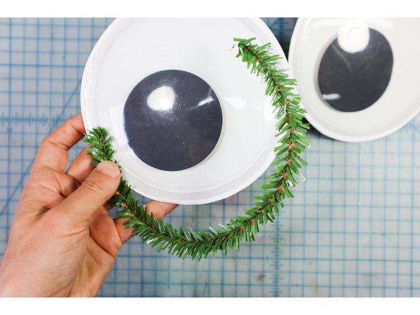 Glue evergreen pipe cleaners around the eyes as shown.