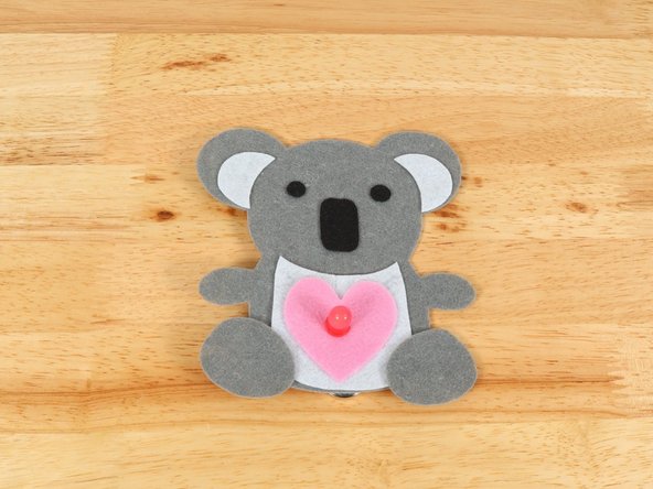 To make the Koala Bear look like it is holding the heart, fold the paws inward and keep them in place with a small amount of hot glue.