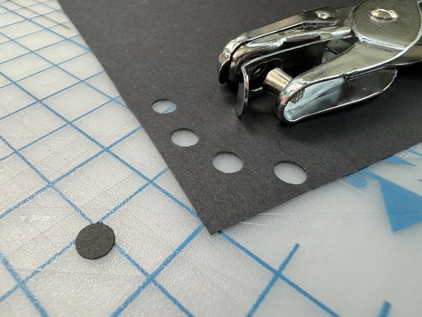 Use a hole punch to make a small black circle from a piece of black paper.