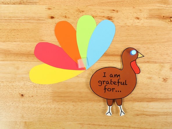 Make a tape loop of clear tape and attach the feathers to the back of the turkey.