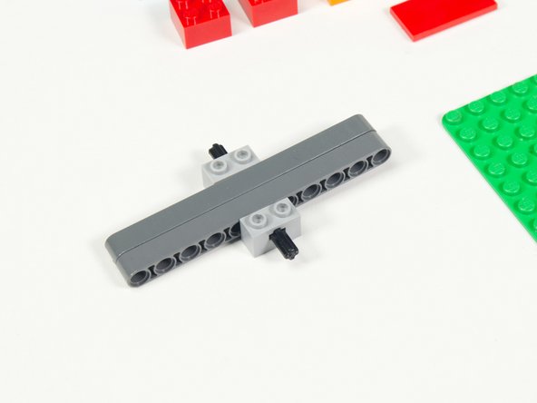 Place the axle through the two beams at the center with the two 1 x 2 bricks with axle holes on either side.