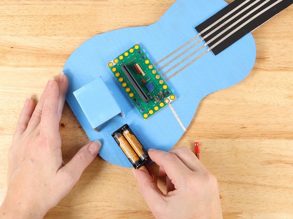 Slide the Battery Pack into the compartment and secure it in place with a rubber band.