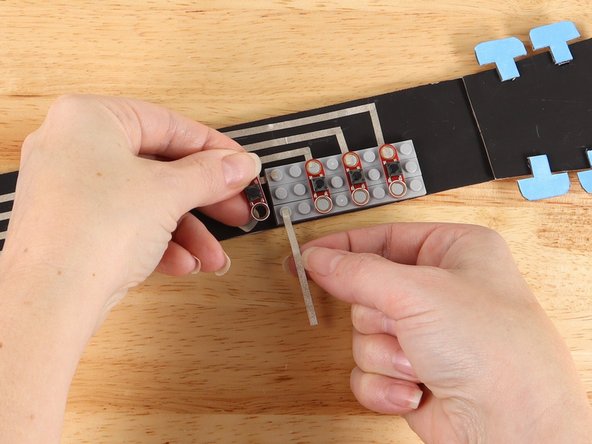 Remove the first button and add a piece of Maker Tape to the bottom stud as pictured.