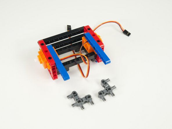 Add the two gray 90 degree connectors to the blue rear stabilizer beams as shown so the pins are facing towards the rear of the rover.