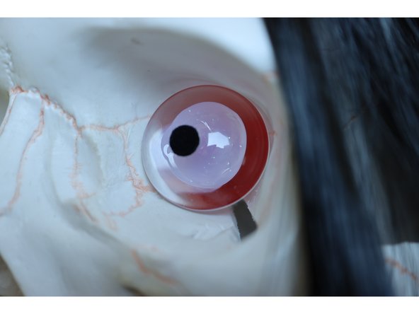 Use a large blob of hot glue on the back of a glass dome to cover the LEDs in the eyes as shown.