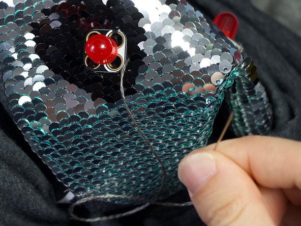 Turn the shirt right side out. Sew a few finishing stitches to the negative hole of the second LED.