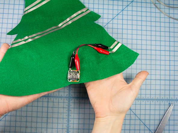 Using some green thread, sew the battery pack near the bottom of the tree so that you can easily remove the battery when it needs to be replaced.