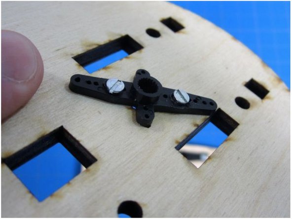 Using two of the very small screws, attach a Servo Horn to the bottom of the circular wooden piece.